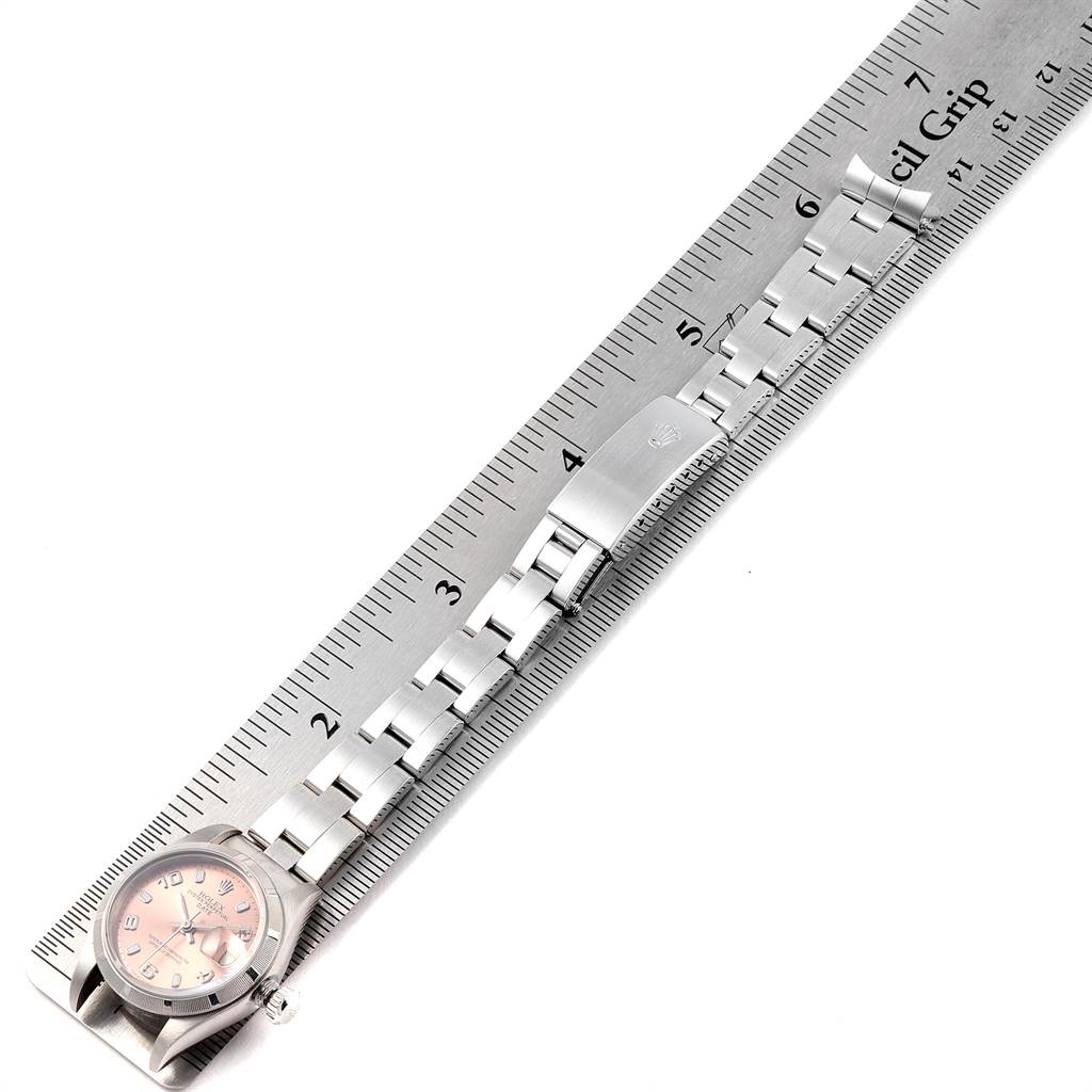 The image shows a top-down view of a Rolex Date 79190 Women
s Stainless Steel Pink Dial 79190 Women
s Stainless Steel Pink Dial model watch with a ruler measuring its stainless steel bracelet.