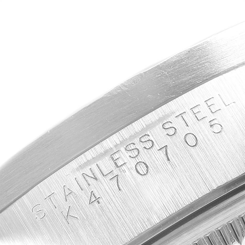 This close-up image shows the side of the stainless steel caseback of a Rolex Date 15210 Men's Stainless Steel Blue Dial 15210 Men's Stainless Steel Blue Dial model watch, featuring engraved text.