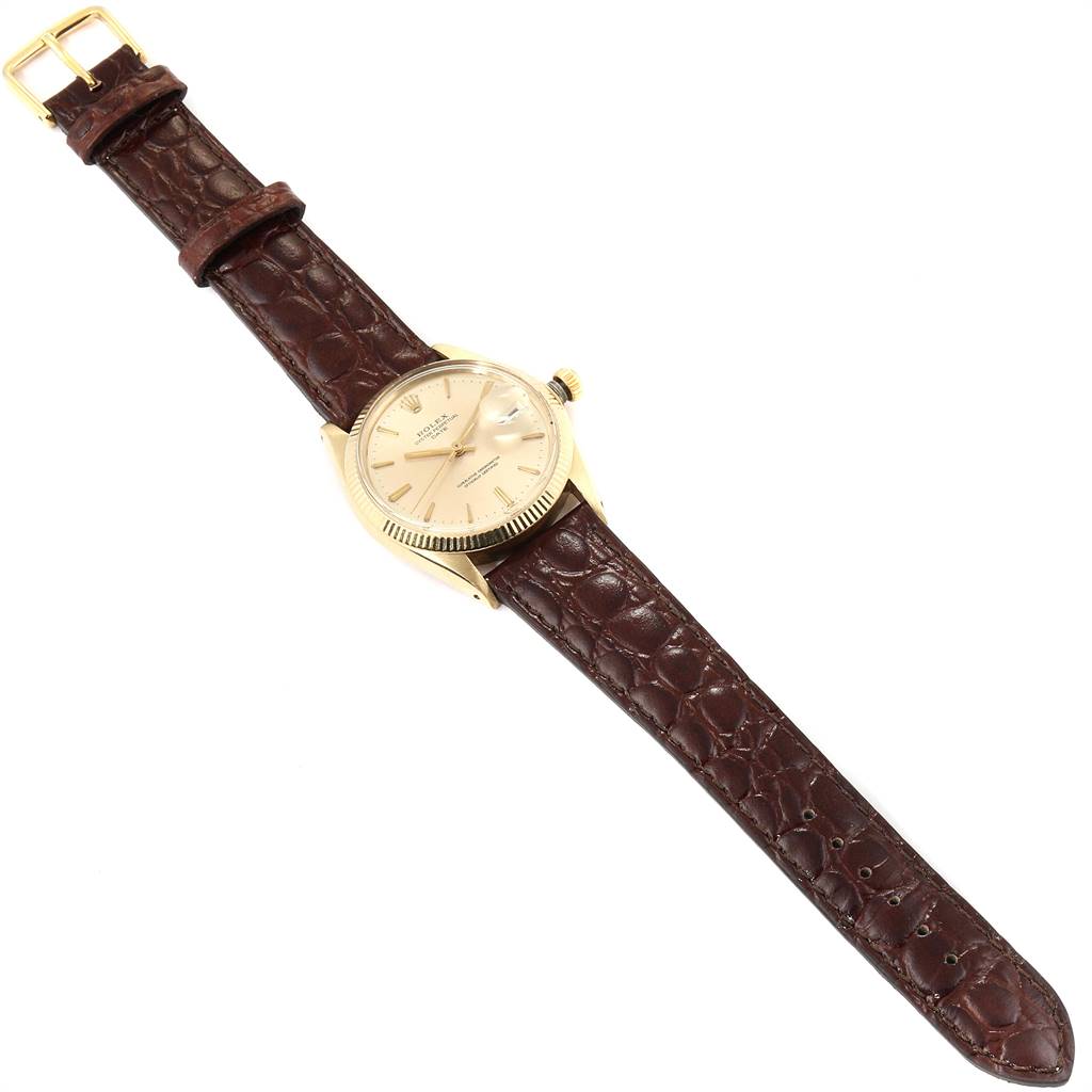 This image shows a Rolex Date 1503 Men's Yellow Gold Champagne Dial 1503 Men's Yellow Gold Champagne Dial model watch at an angled overhead view, highlighting its beige dial, gold case, and brown leather strap.