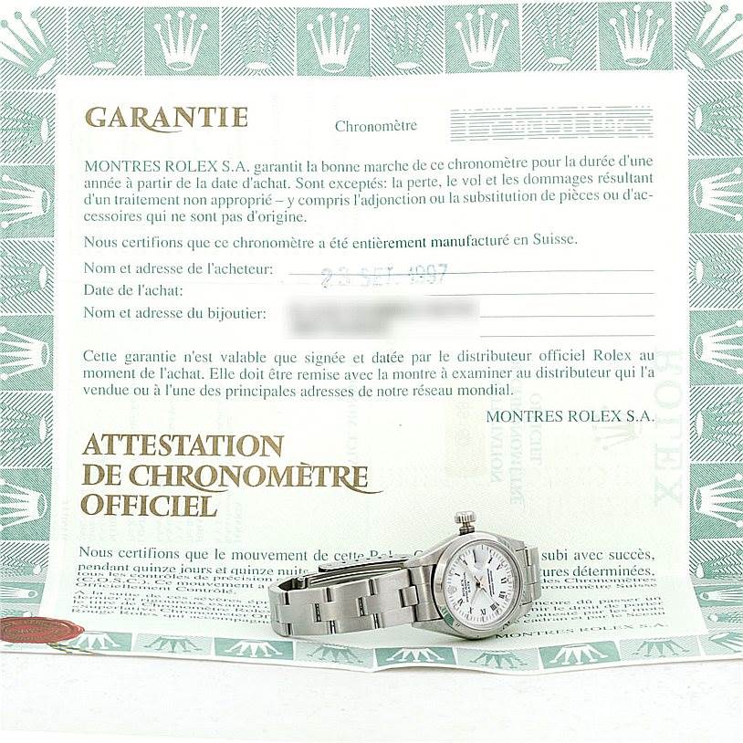 The image shows a Rolex Date 69160 Women's Stainless Steel White Dial 69160 Women's Stainless Steel White Dial model watch positioned at an angle, displaying its side and bracelet, alongside the warranty card.