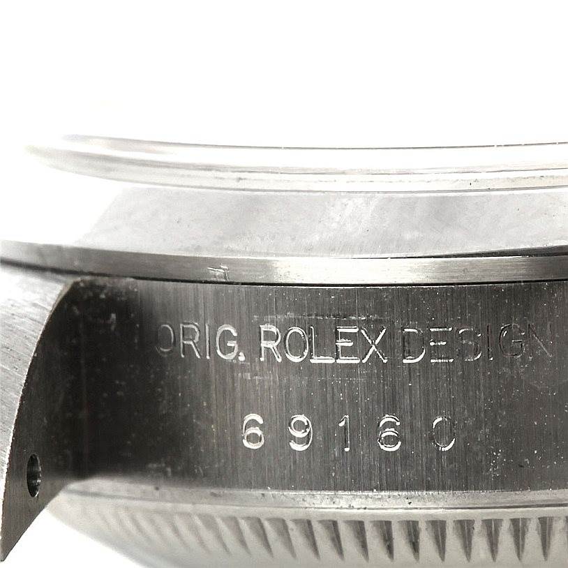 The image shows a close-up of the case side and bezel of a Rolex Date 69160 Women's Stainless Steel White Dial 69160 Women's Stainless Steel White Dial model, showcasing the engraved serial number and watch design.