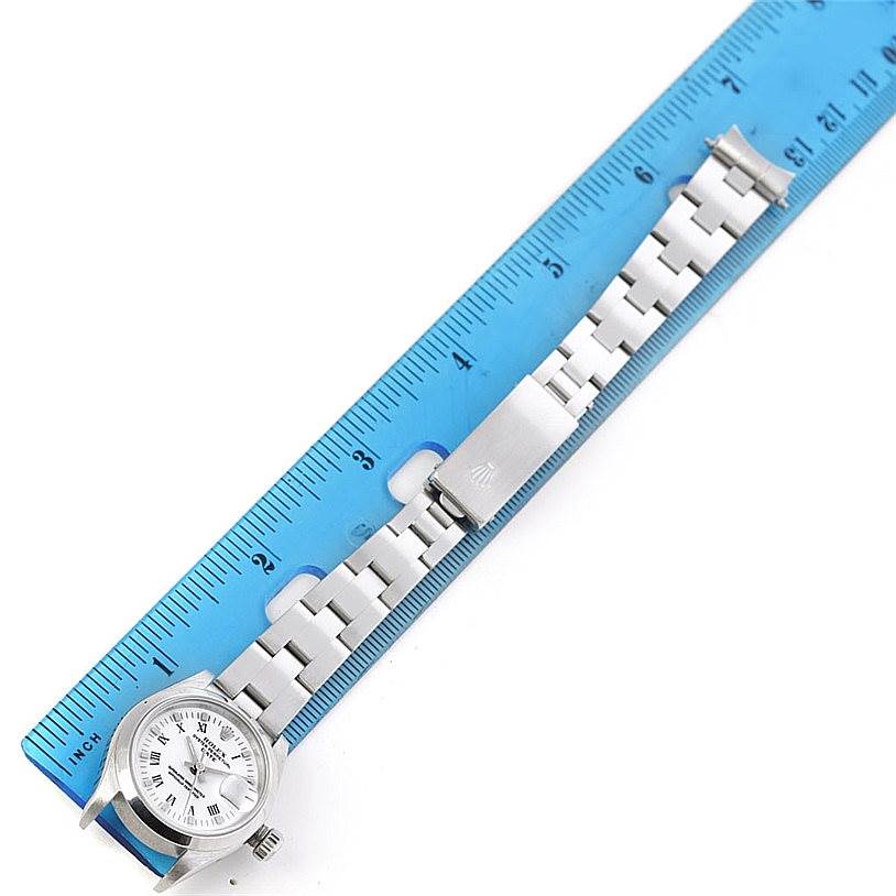 The image shows a Rolex Date 69160 Women's Stainless Steel White Dial 69160 Women's Stainless Steel White Dial watch model placed next to a blue ruler, displaying the watch face, band, and clasp.