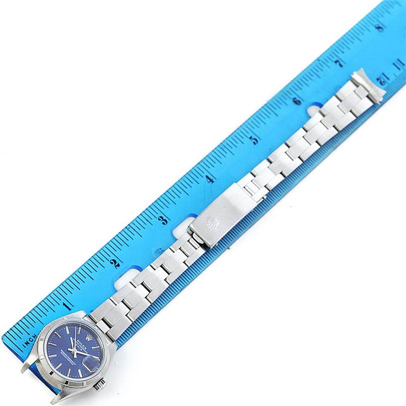 The image shows a top-down view of a Rolex Date 79190 Women's Stainless Steel Blue Dial 79190 Women's Stainless Steel Blue Dial model watch, featuring its face, bracelet, and clasp next to a ruler for scale.