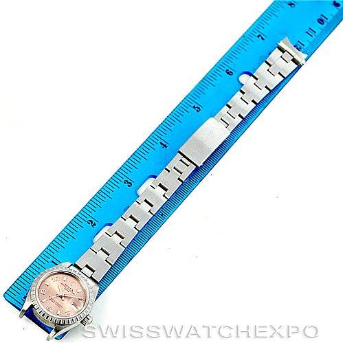 The image shows a Rolex Date 79240 Women's Stainless Steel Pink Dial 79240 Women's Stainless Steel Pink Dial model watch laid out flat next to a blue ruler, displaying its metal bracelet and face.