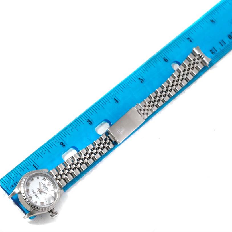 The image shows a top view of a Rolex Date 79240 Women's Stainless Steel White Dial 79240 Women's Stainless Steel White Dial model watch with its bracelet laid alongside a blue ruler.