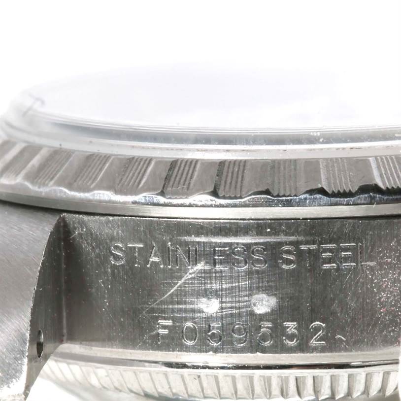 This close-up image of a Rolex Date 79240 Women's Stainless Steel White Dial 79240 Women's Stainless Steel White Dial model shows the side view of the case, bezel, and part of the crystal with the serial number engraved.