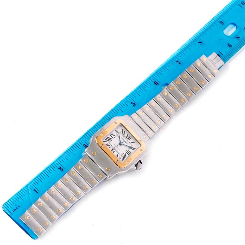 The Cartier Santos W20099C4 Men
s Stainless Steel Silver Dial W20099C4 Men
s Stainless Steel Silver Dial watch is shown from a top-down angle alongside a blue ruler for scale.