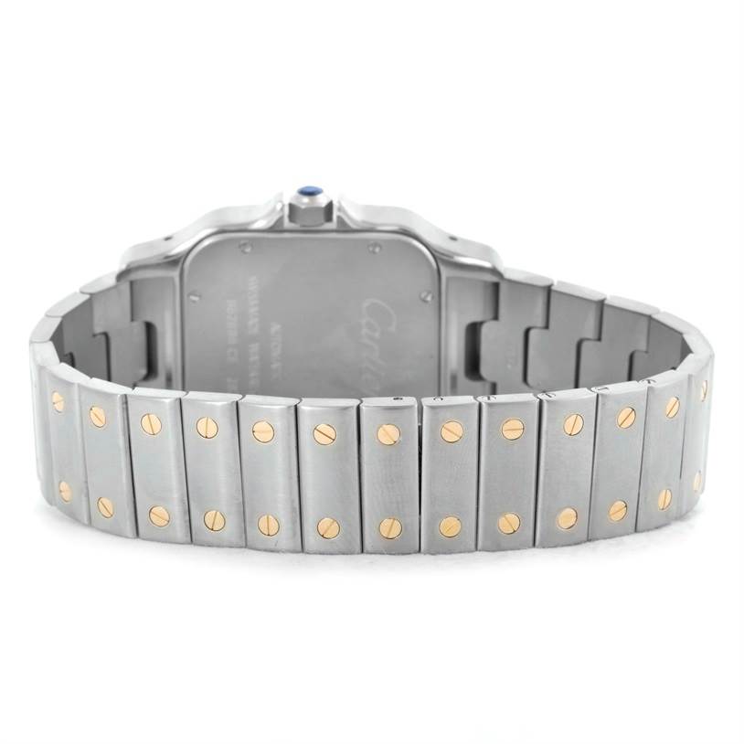 The image shows the back case and bracelet of a Santos model by Cartier, highlighting the metal strap with gold screws.