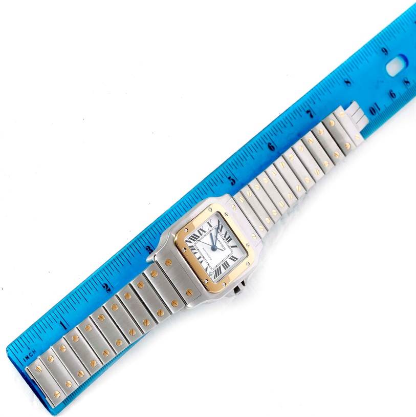 This image shows an overhead view of a Cartier Santos W20099C4 Men
s Stainless Steel Silver Dial W20099C4 Men
s Stainless Steel Silver Dial watch alongside a blue ruler.