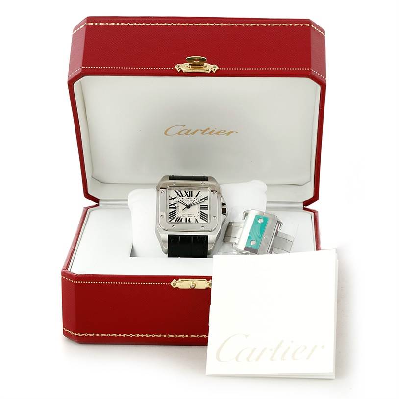 The Cartier Santos W20073X8 Men's Stainless Steel Silver Dial W20073X8 Men's Stainless Steel Silver Dial watch is shown from the front inside an open red Cartier box, with additional watch accessories and booklets.