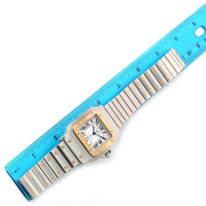 The image shows a Cartier Santos W20099C4 Men's Stainless Steel Silver Dial W20099C4 Men's Stainless Steel Silver Dial watch face and entire bracelet, evenly aligned with a blue ruler for measurement.