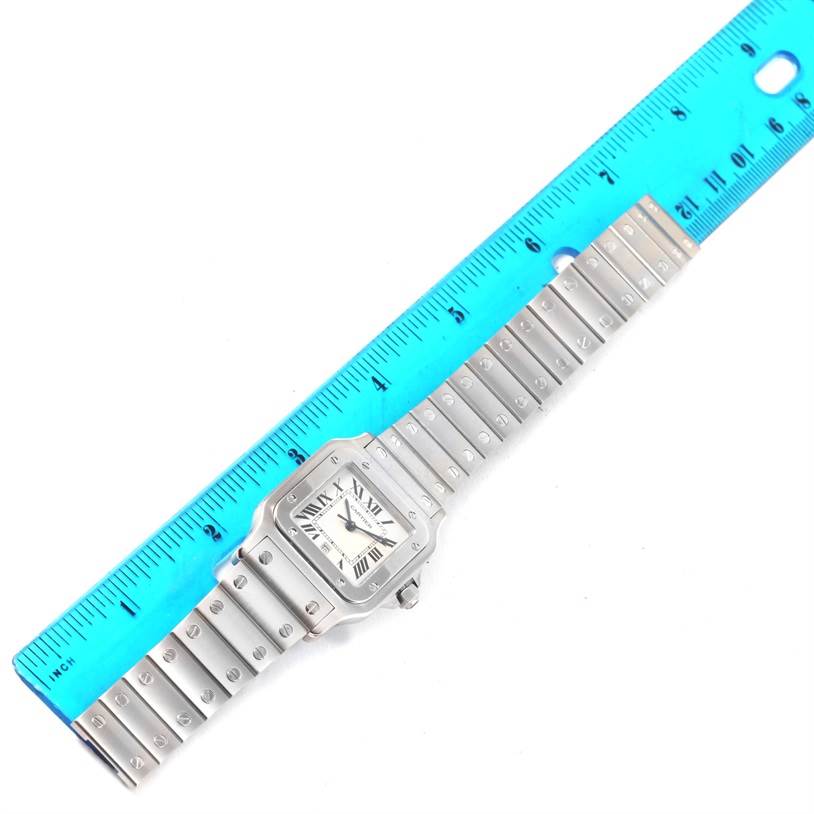 The image shows a Cartier Santos W20060D6 Men
s Stainless Steel Silver Dial W20060D6 Men
s Stainless Steel Silver Dial watch laid flat, positioned next to a blue ruler for measurement.