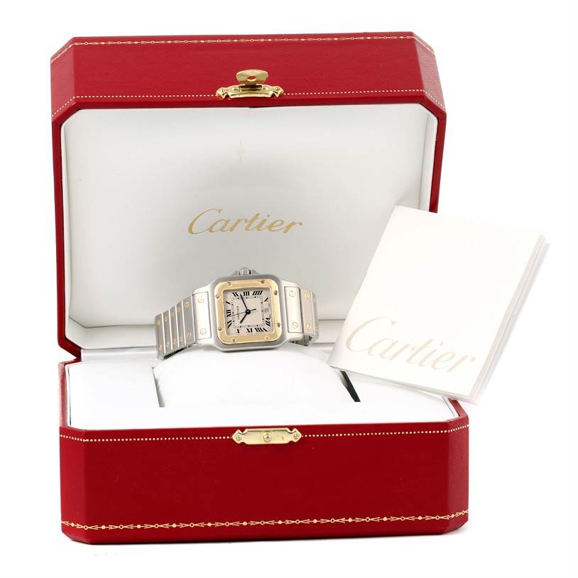 The image shows a Cartier Santos W20011C4 Stainless Steel Silver Dial W20011C4 Stainless Steel Silver Dial watch presented in an open red Cartier box with a Cartier booklet.