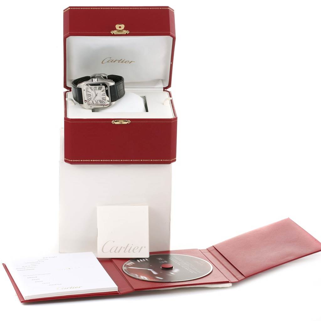 The Cartier Santos W20073X8 Men's Stainless Steel Silver Dial W20073X8 Men's Stainless Steel Silver Dial watch is displayed in an open box along with a booklet, CD, and packaging materials.