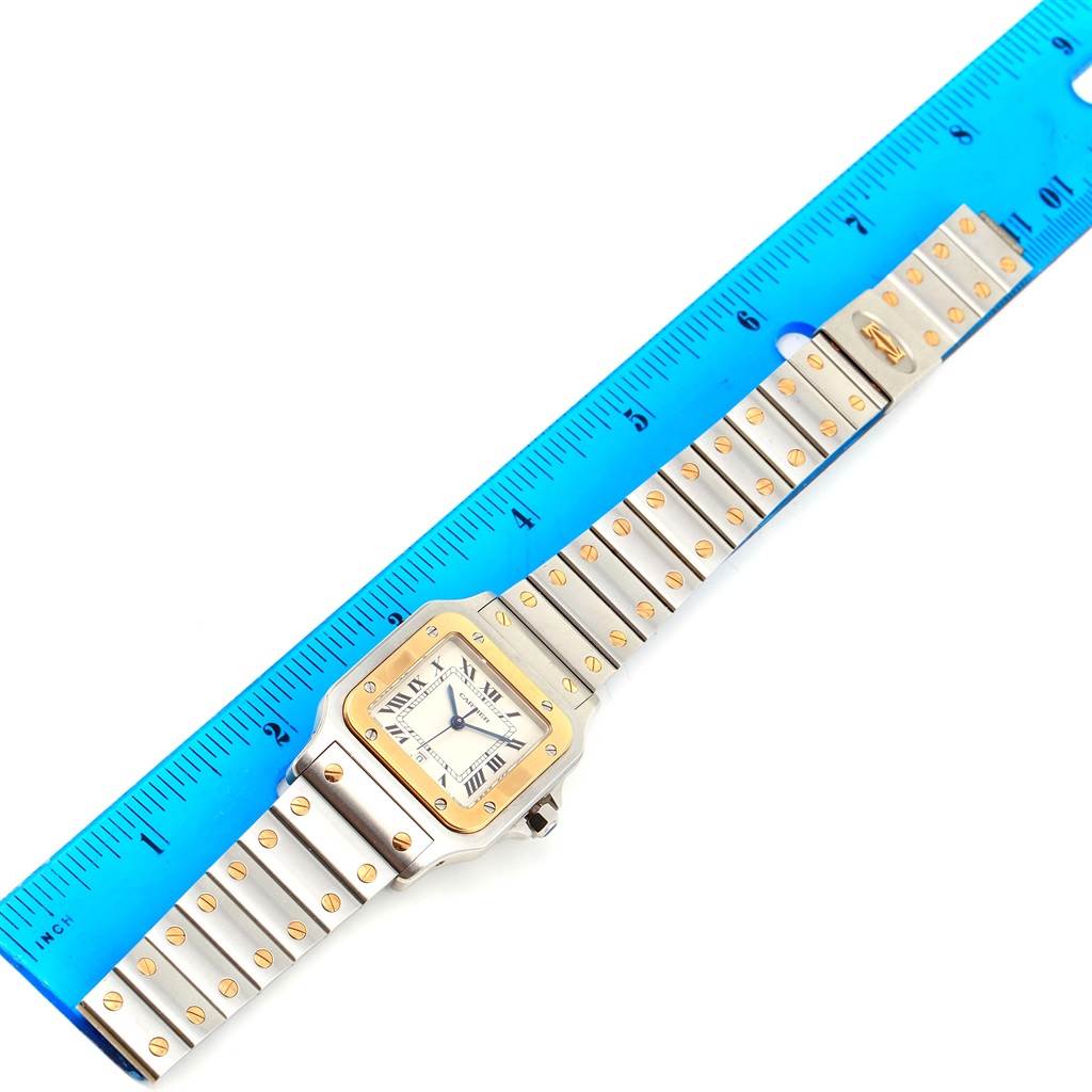 The image shows a full Santos model watch by Cartier, laid flat next to a ruler for measurement.