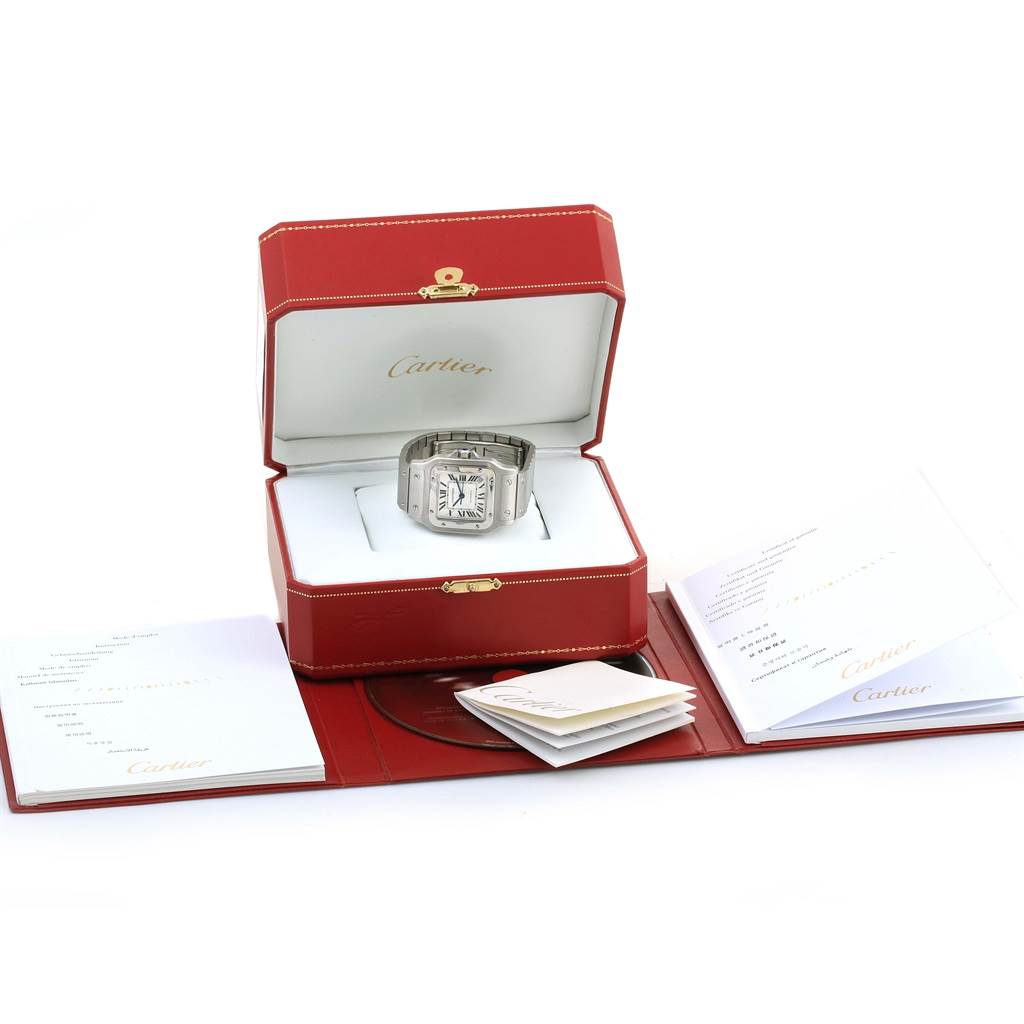 The image shows a Cartier Santos W20098D6 Men
s Stainless Steel Silver Dial W20098D6 Men
s Stainless Steel Silver Dial watch presented in an open red box with accompanying booklets displayed around it.