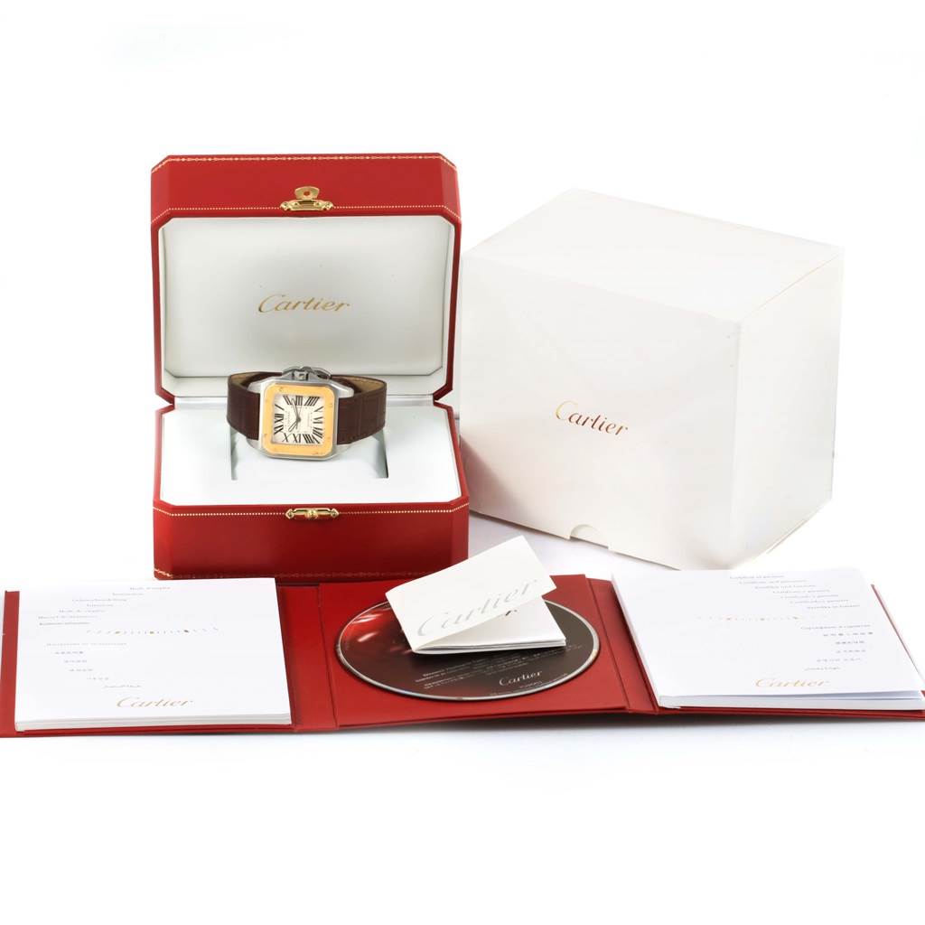 The image shows a Cartier Santos W20072X7 Men
s Stainless Steel Silver Dial W20072X7 Men
s Stainless Steel Silver Dial watch in its open red box, with a white outer box, manual, and CD laid out in front.