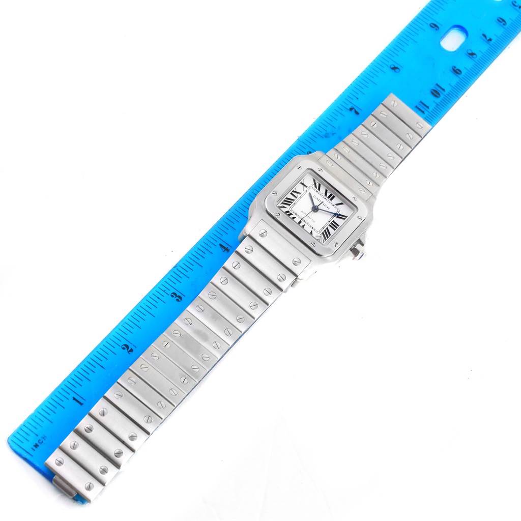 This image shows the Santos model watch by Cartier laid flat with a blue ruler next to it.
