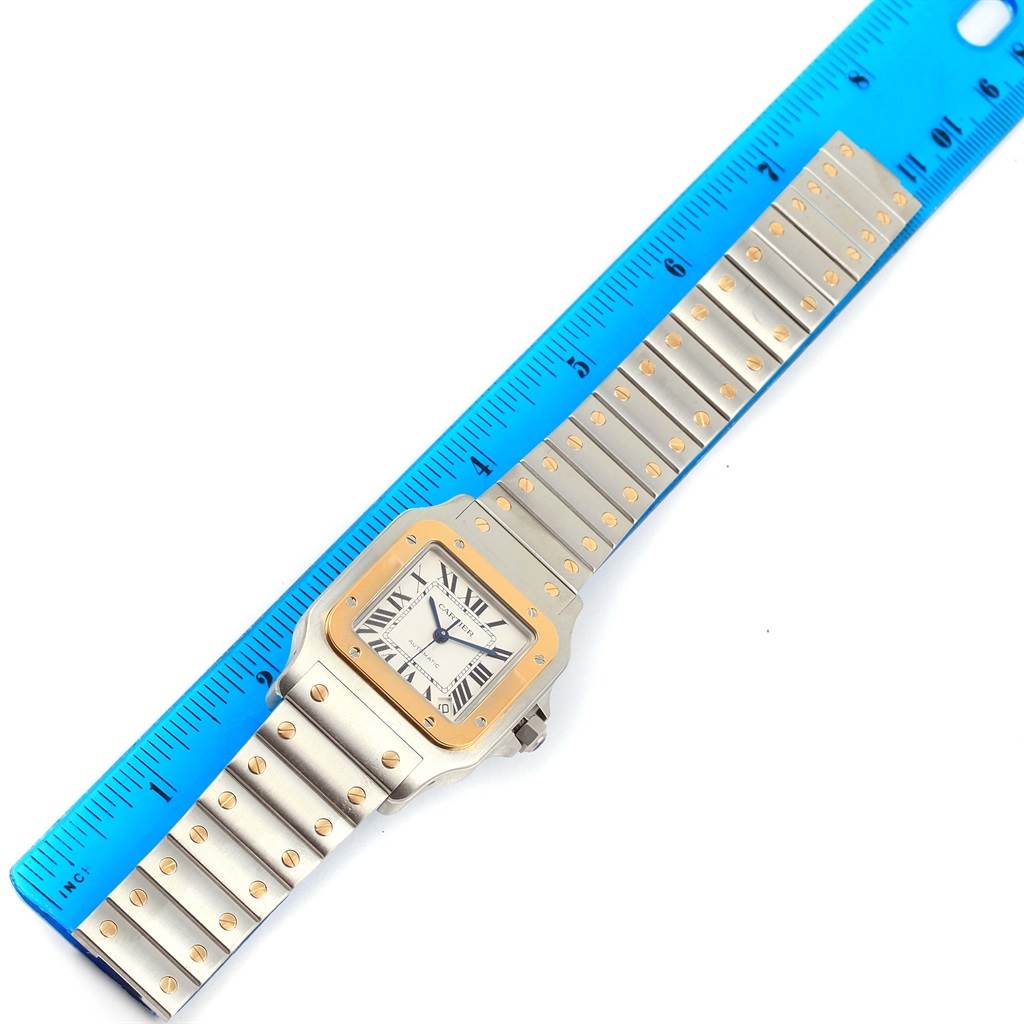 The image shows a Cartier Santos W20099C4 Men
s Stainless Steel Silver Dial W20099C4 Men
s Stainless Steel Silver Dial watch laid flat with a blue ruler measuring its length.