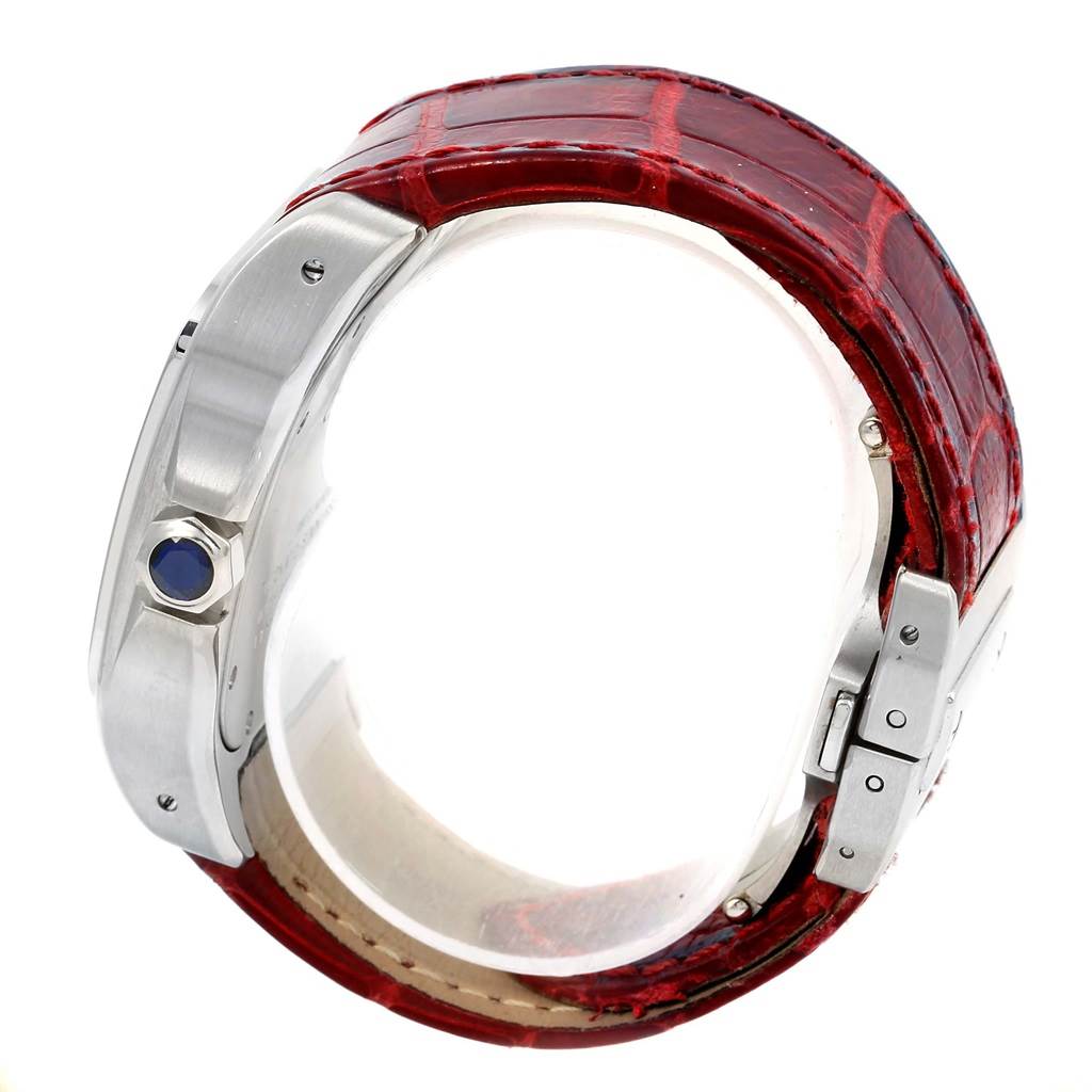 The image shows a side view of a Cartier Santos W20073X8 Men
s Stainless Steel Silver Dial W20073X8 Men
s Stainless Steel Silver Dial watch, highlighting its case, crown with blue cabochon, and red leather strap.