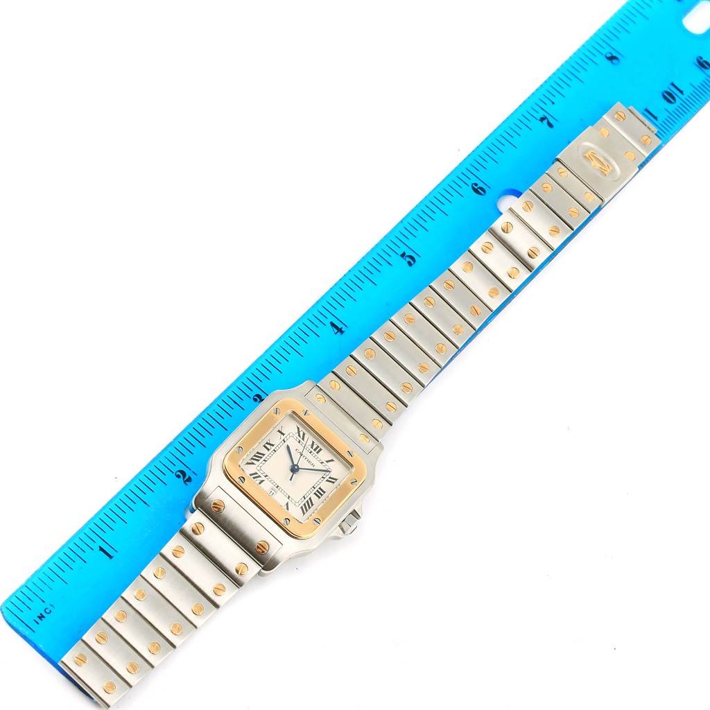 The image shows an overhead view of a Cartier Santos 187901 Men
s Stainless Steel Silver Dial 187901 Men
s Stainless Steel Silver Dial watch, displaying the face, case, and bracelet with a ruler alongside it.