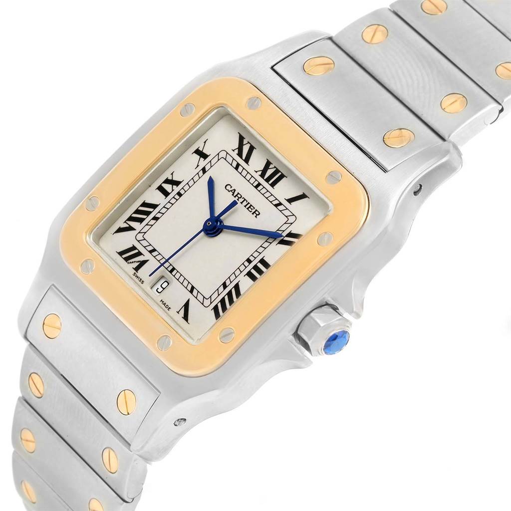 This image shows a close-up of the Cartier Santos 187901 Men
s Stainless Steel Silver Dial 187901 Men
s Stainless Steel Silver Dial watch face and part of the metal strap, featuring gold accents and a crown.