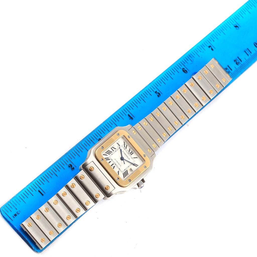 The image shows a Cartier Santos W20058C4 Stainless Steel Silver Dial W20058C4 Stainless Steel Silver Dial watch laid flat next to a blue ruler for scale.