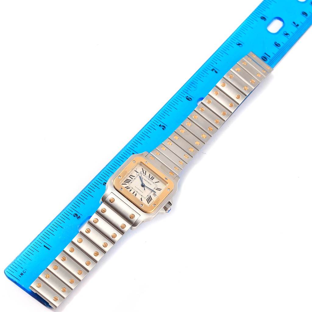 The photo shows a Cartier Santos W20058C4 Men
s Stainless Steel Silver Dial W20058C4 Men
s Stainless Steel Silver Dial watch laid flat next to a blue ruler for size reference.