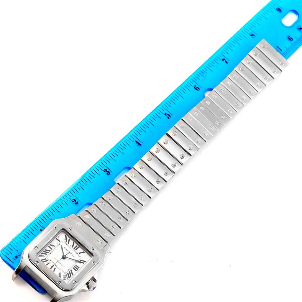 The image shows a Cartier Santos W20098D6 Men's Stainless Steel Silver Dial W20098D6 Men's Stainless Steel Silver Dial watch placed next to a blue ruler, emphasizing the watch's band length.