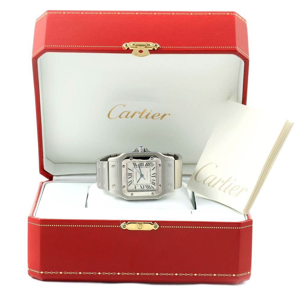 The image shows a Cartier Santos W20098D6 Men's Stainless Steel Silver Dial W20098D6 Men's Stainless Steel Silver Dial watch placed in an open red Cartier box with a booklet beside it, viewed from the front.