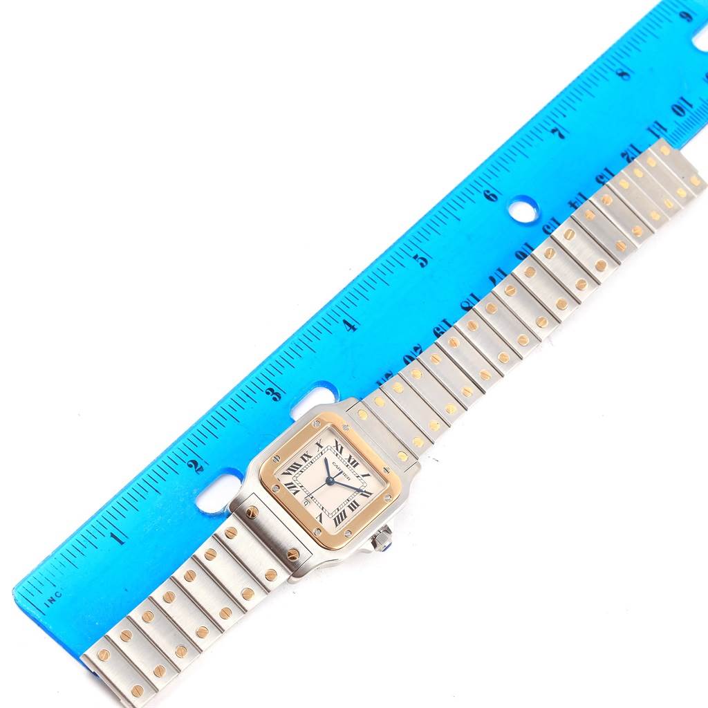 The Cartier Santos W20011C4 Stainless Steel Silver Dial W20011C4 Stainless Steel Silver Dial watch is shown from a top-down angle, alongside a blue ruler for scale.