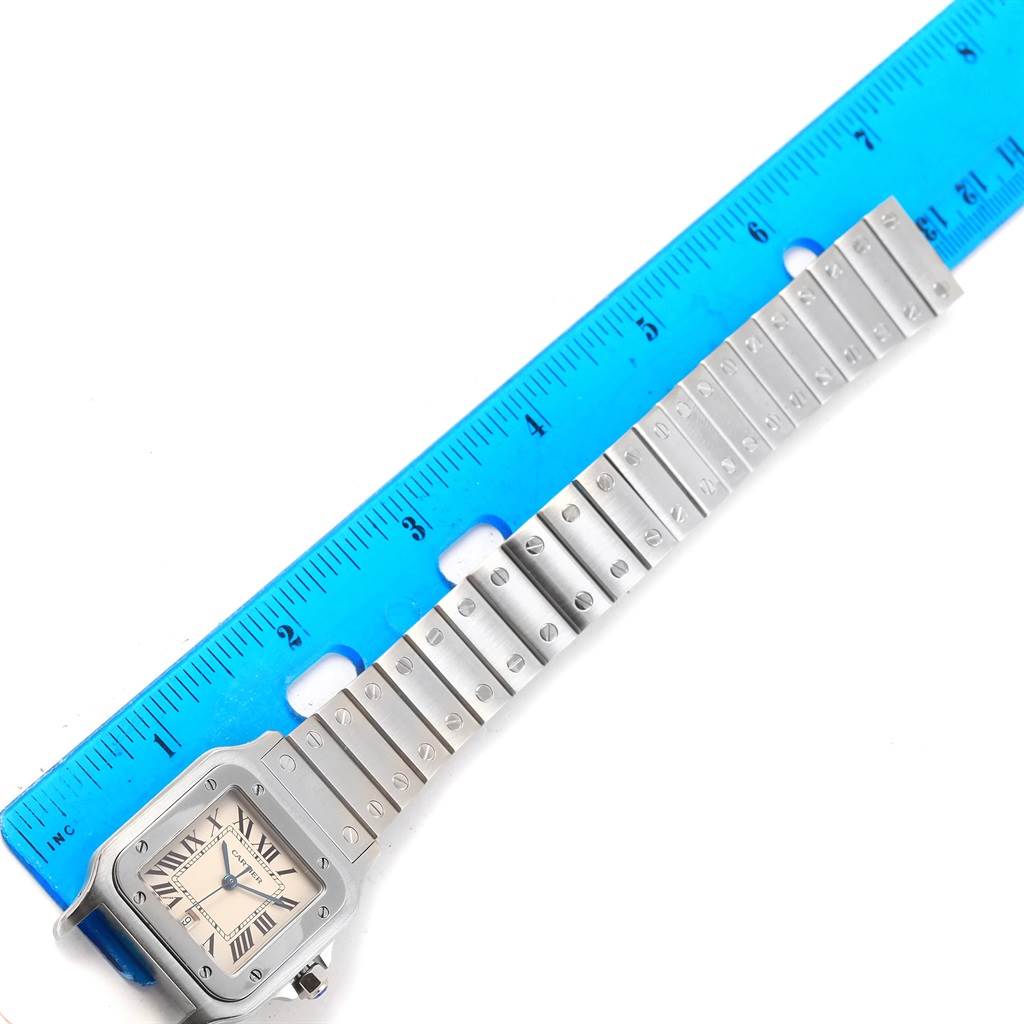 The Cartier Santos W20060D6 Stainless Steel Silver Dial W20060D6 Stainless Steel Silver Dial watch is shown from the front with the band extended next to a blue ruler for scale.
