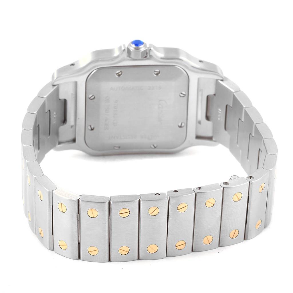 The image shows the back and bracelet of a Santos by Cartier watch, featuring a metallic finish with gold screw accents.