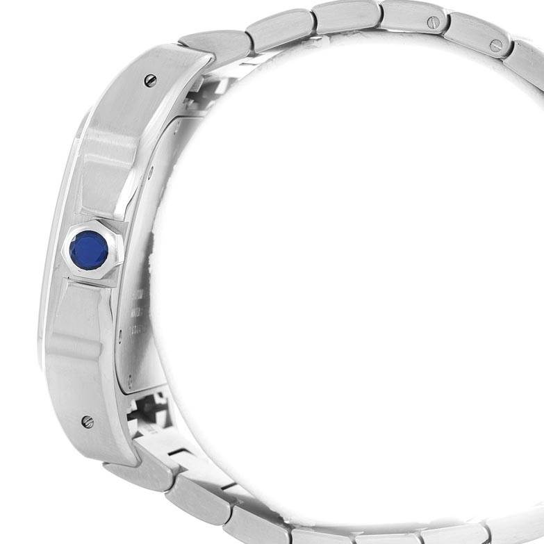 The image shows a side view of a Santos model watch by Cartier, highlighting its metallic bracelet and blue crown.