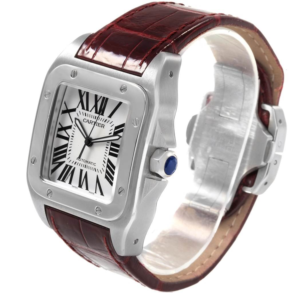 The image shows a Cartier Santos W20073X8 Men's Stainless Steel Silver Dial W20073X8 Men's Stainless Steel Silver Dial watch, highlighting its face, bezel, case, crown with blue gem, and leather strap.