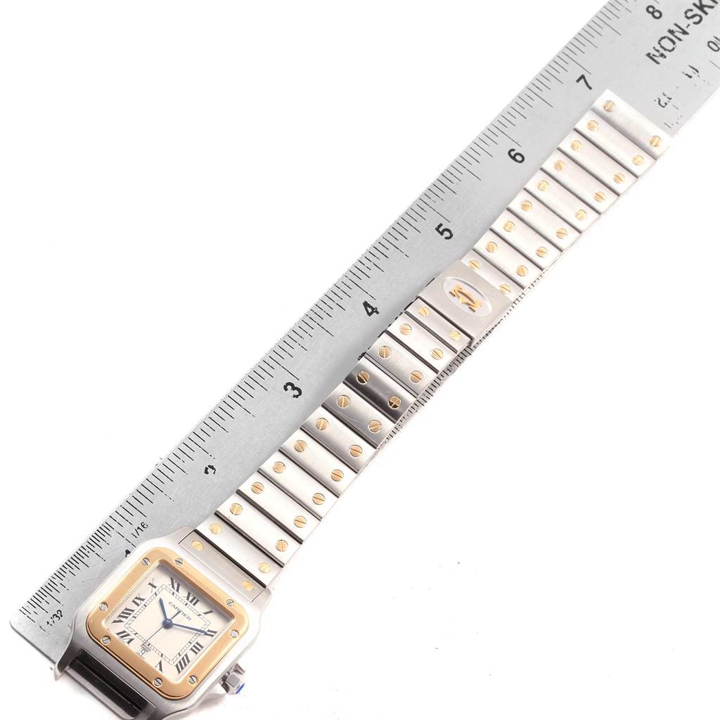 The image shows the front of a Cartier Santos 1566 Stainless Steel Silver Dial 1566 Stainless Steel Silver Dial watch laying flat with its band extended, measured next to a ruler.