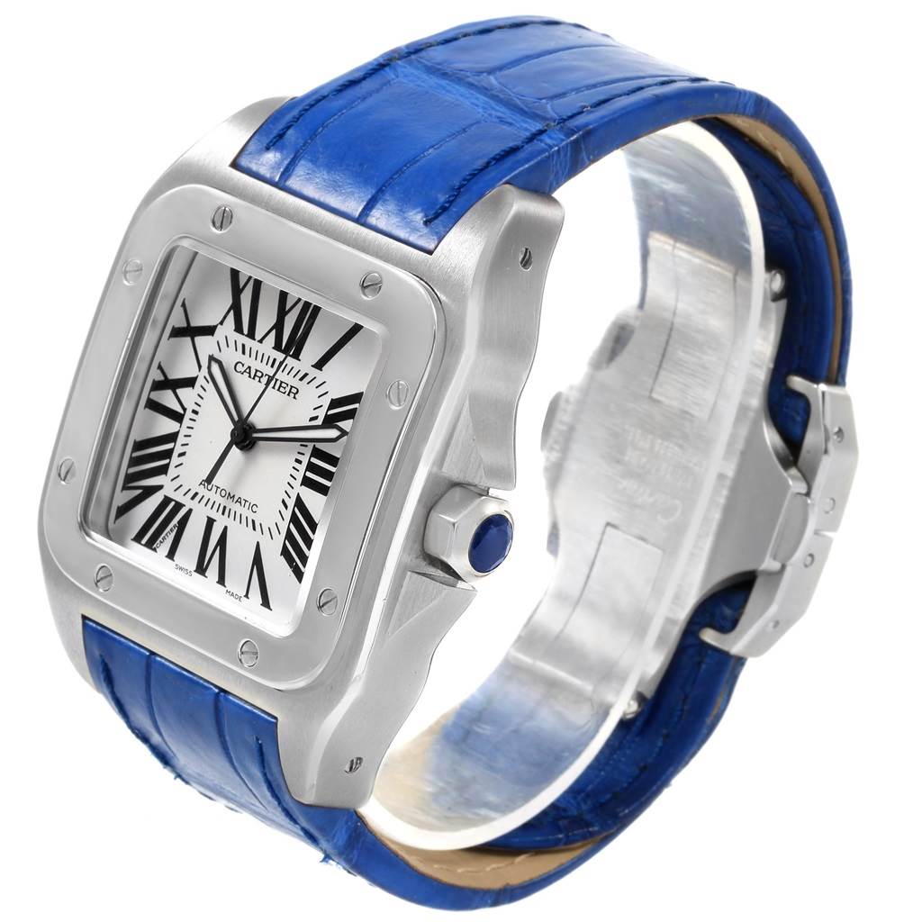 The Cartier Santos W20073X8 Men
s Stainless Steel Silver Dial W20073X8 Men
s Stainless Steel Silver Dial watch is shown at an angled side view, highlighting its square face, blue strap, and crown.