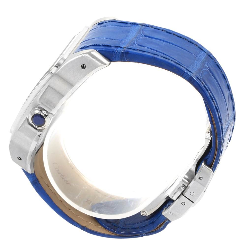 The image shows a side view of a Cartier Santos W20073X8 Men
s Stainless Steel Silver Dial W20073X8 Men
s Stainless Steel Silver Dial watch with a blue leather strap and a visible crown with a blue stone.