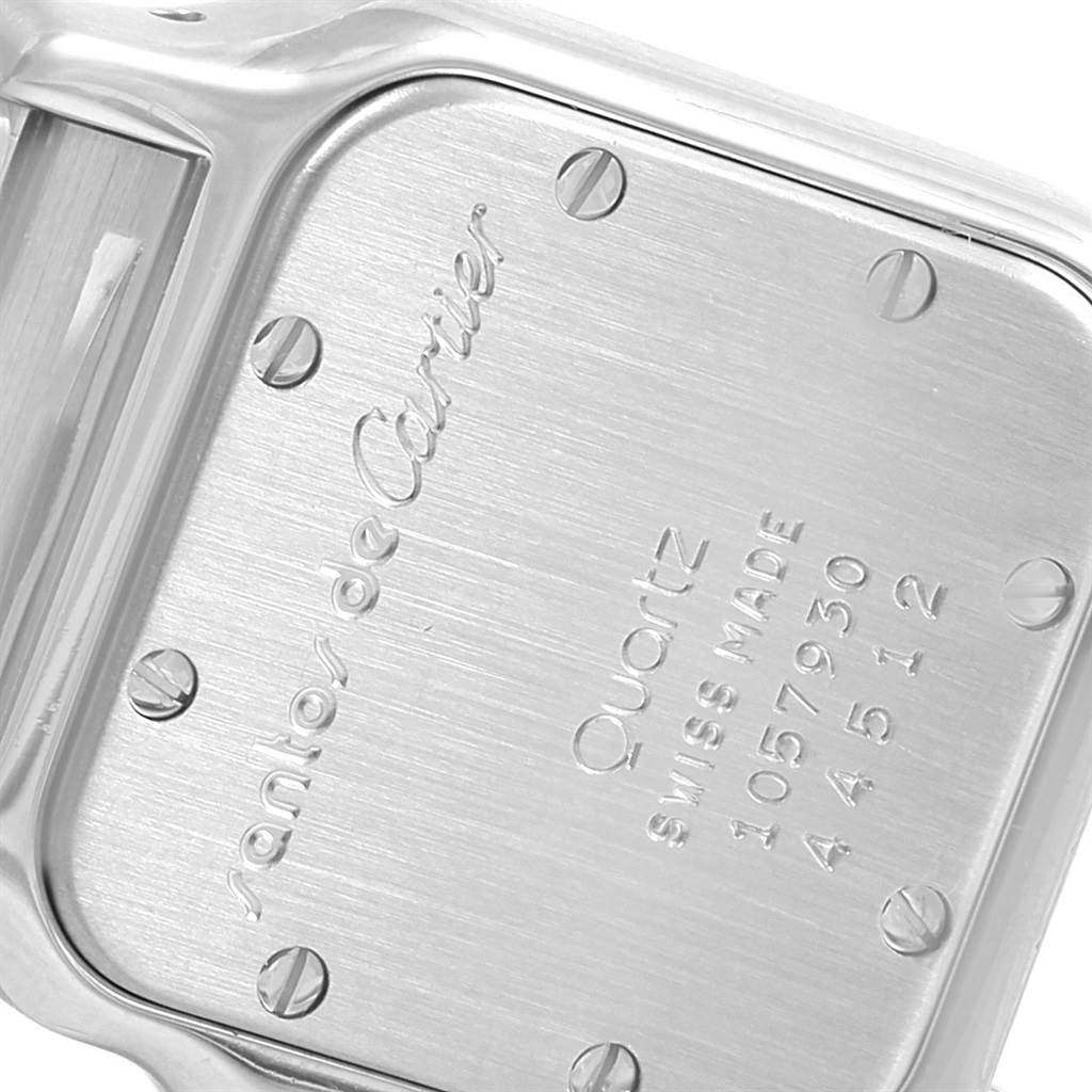 This close-up image shows the case back of a Santos model by Cartier, featuring the brand and model engravings.