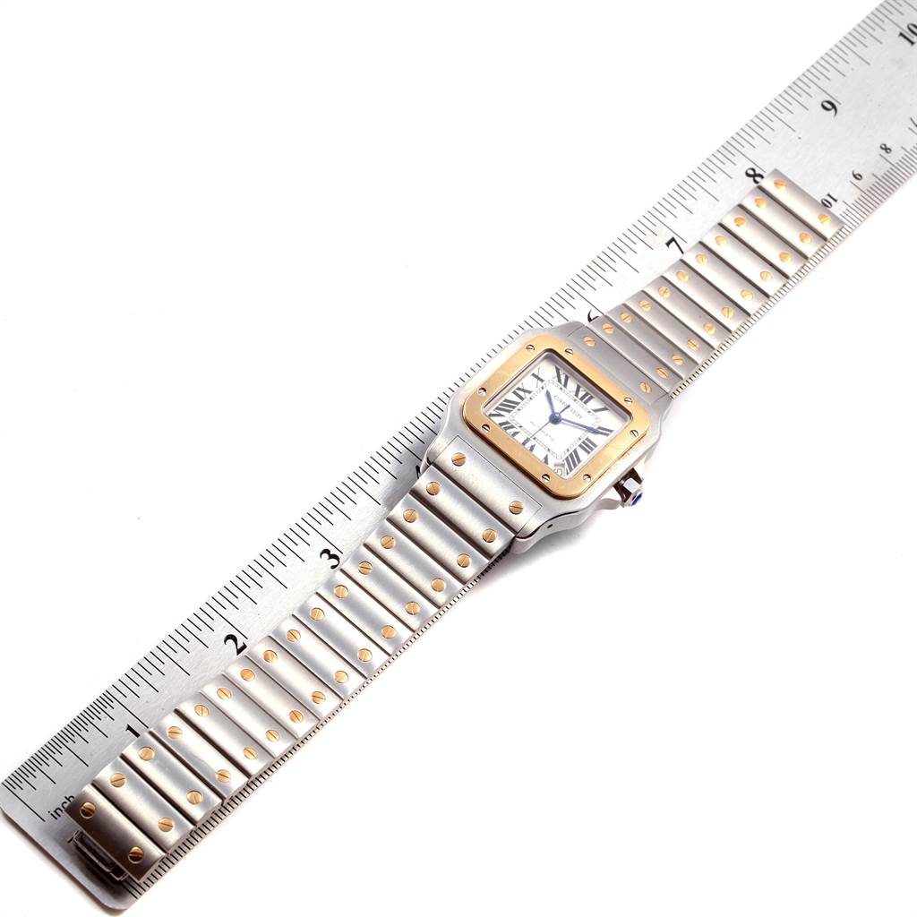 The Cartier Santos W20099C4 Men's Stainless Steel Silver Dial W20099C4 Men's Stainless Steel Silver Dial watch is shown from an overhead angle, displaying the face and bracelet along with a measurement ruler.