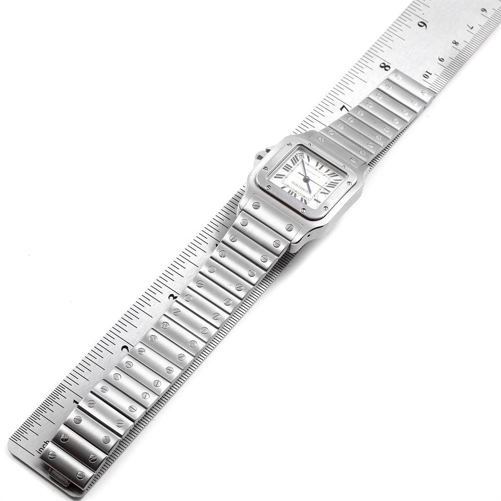 The image shows a Cartier Santos W20098D6 Men's Stainless Steel Silver Dial W20098D6 Men's Stainless Steel Silver Dial watch lying flat next to a ruler, displaying its face and metal bracelet.