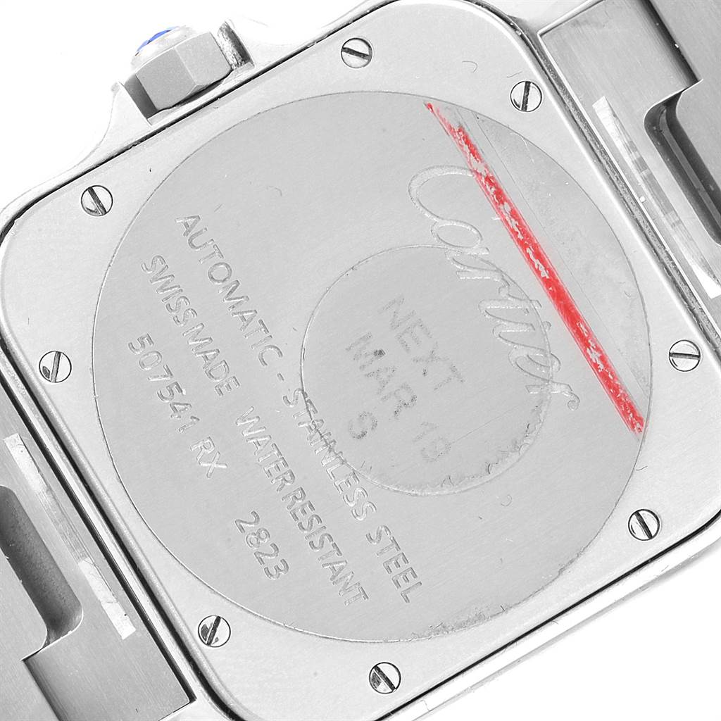 The image shows the case back of a Santos model watch by Cartier, featuring engravings and screws.