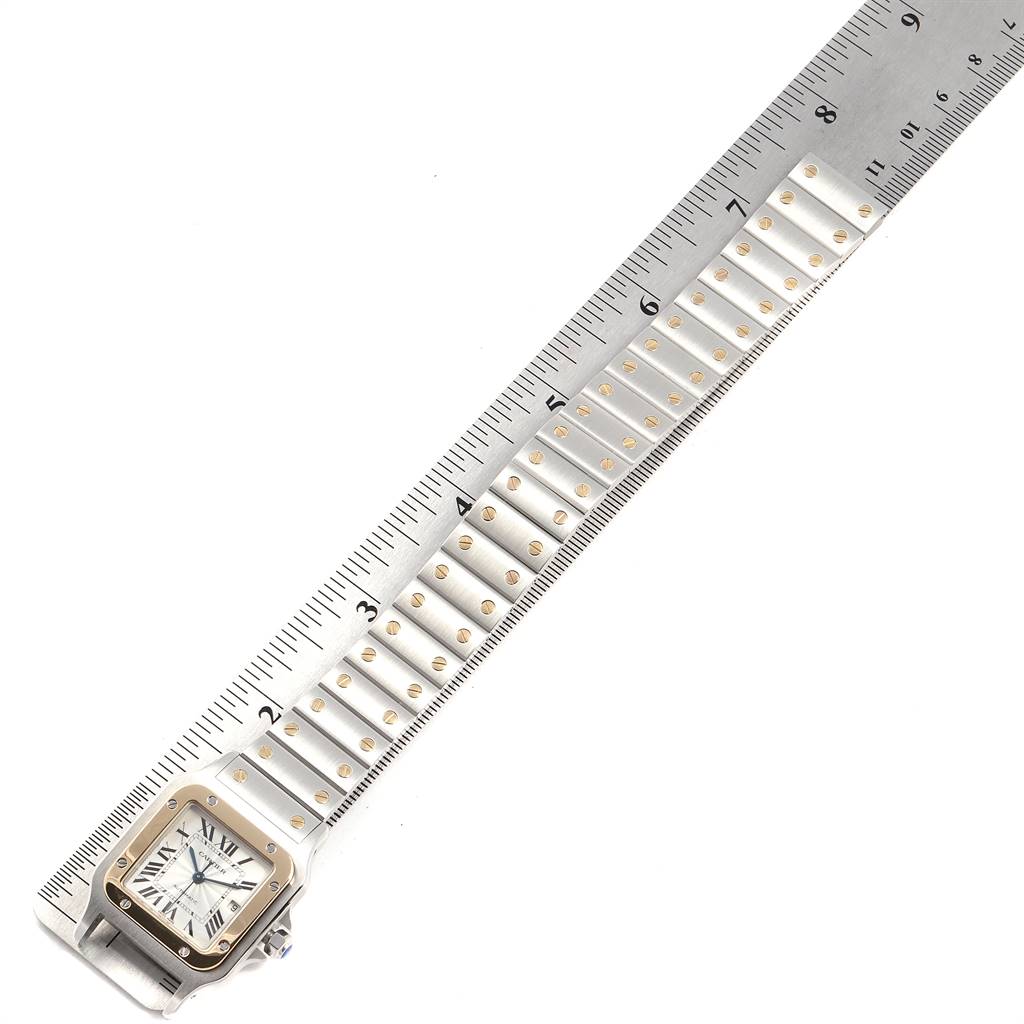 The image shows a Cartier Santos W20058C4 Men's Stainless Steel Silver Dial W20058C4 Men's Stainless Steel Silver Dial watch placed alongside a ruler, highlighting the watch band and square face with Roman numerals.