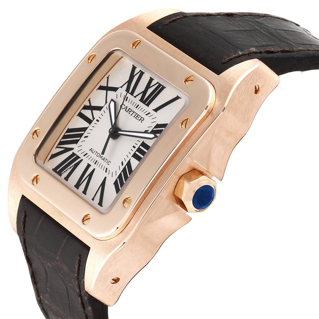 This Cartier Santos W20095Y1 Men's Rose Gold Silver Dial W20095Y1 Men's Rose Gold Silver Dial watch is shown at a three-quarter angle, highlighting its rose gold case, white dial, black Roman numerals, and black strap.