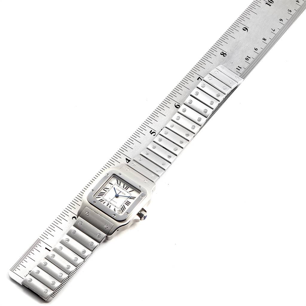 The image shows a Santos model by Cartier watch laid flat with a ruler for scale, highlighting its face and bracelet.