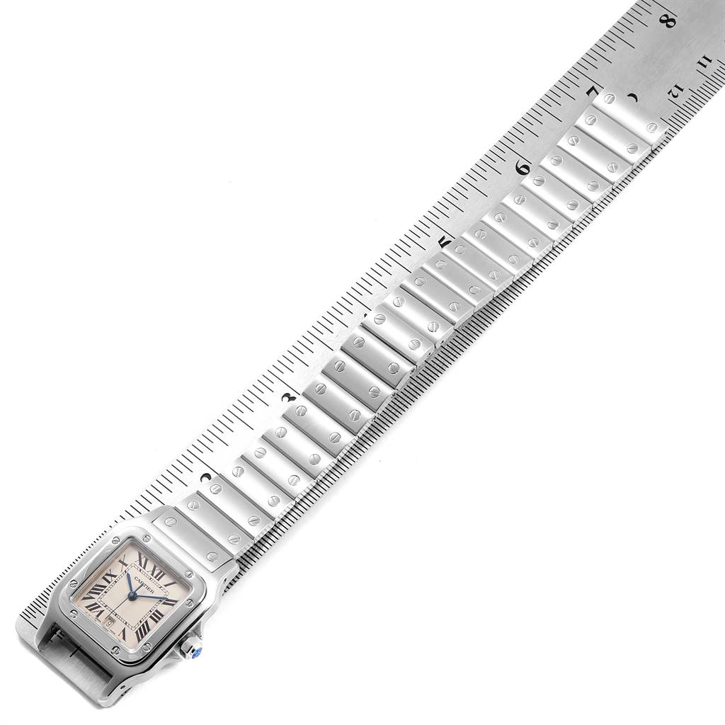 The image shows a Cartier Santos W20060D6 Men's Stainless Steel Silver Dial W20060D6 Men's Stainless Steel Silver Dial watch laid flat on top of a ruler for measurement, displaying the face and part of the metal strap.