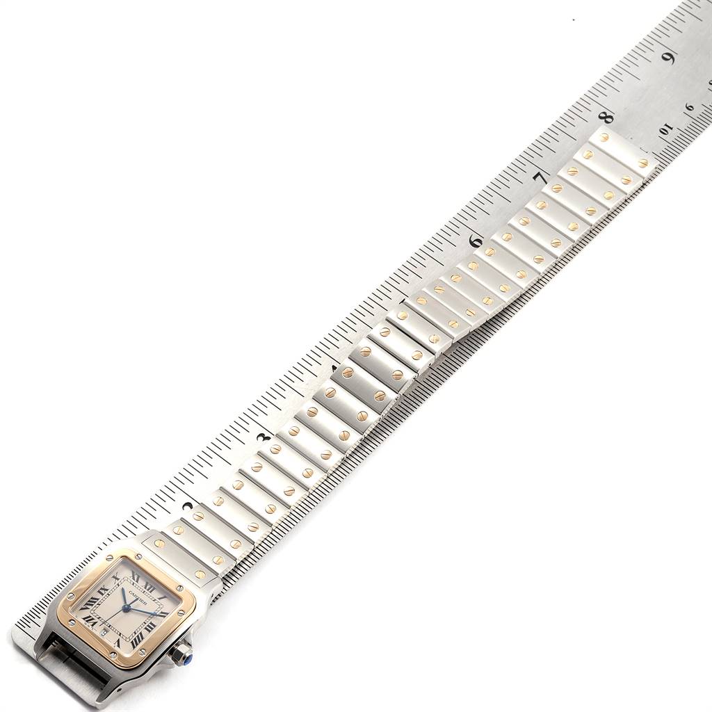 The image shows the side view of a Cartier Santos W20011C4 Stainless Steel Silver Dial W20011C4 Stainless Steel Silver Dial watch, highlighting its squared face and metal bracelet with gold accents.