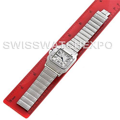 The image shows a Cartier Santos Stainless Steel Silver Dial Stainless Steel Silver Dial watch laid flat next to a red ruler, displaying the face and entire metal bracelet.