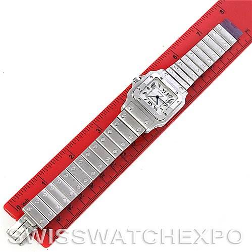 The image shows the Santos model by Cartier laid flat on a red ruler, displaying the watch face and full bracelet.