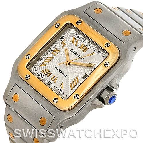 The image shows a close-up, angled view of the Santos model watch by Cartier, focusing on the dial, bezel, and part of the bracelet.